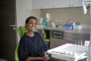cheerful african american woman sitting on dental chair in clinic