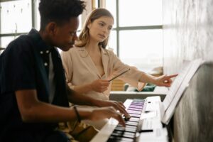 a woman teaching a boy while looking at musical notes